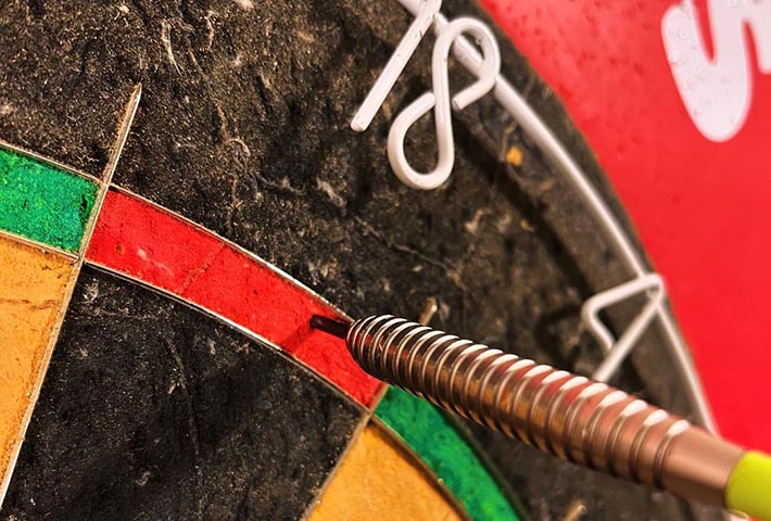 Guest aiming and throwing a dart at the dartboard during a game at Magenta Resort